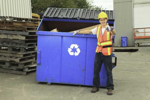 Workers handling commercial waste with safety measures on site