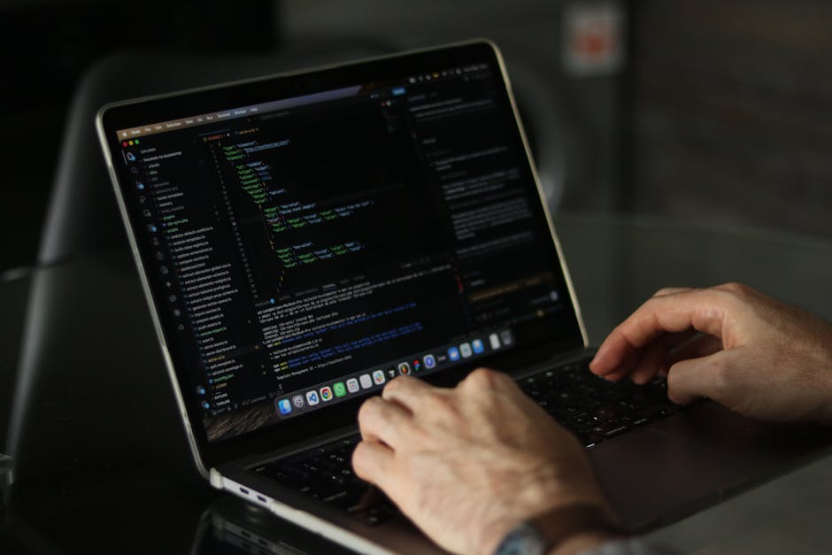 A close-up image of a laptop placed on a wooden desk, displaying lines of code on its screen, with a ceramic coffee mug positioned behind it. The mug is beige with a matte finish and features black pr